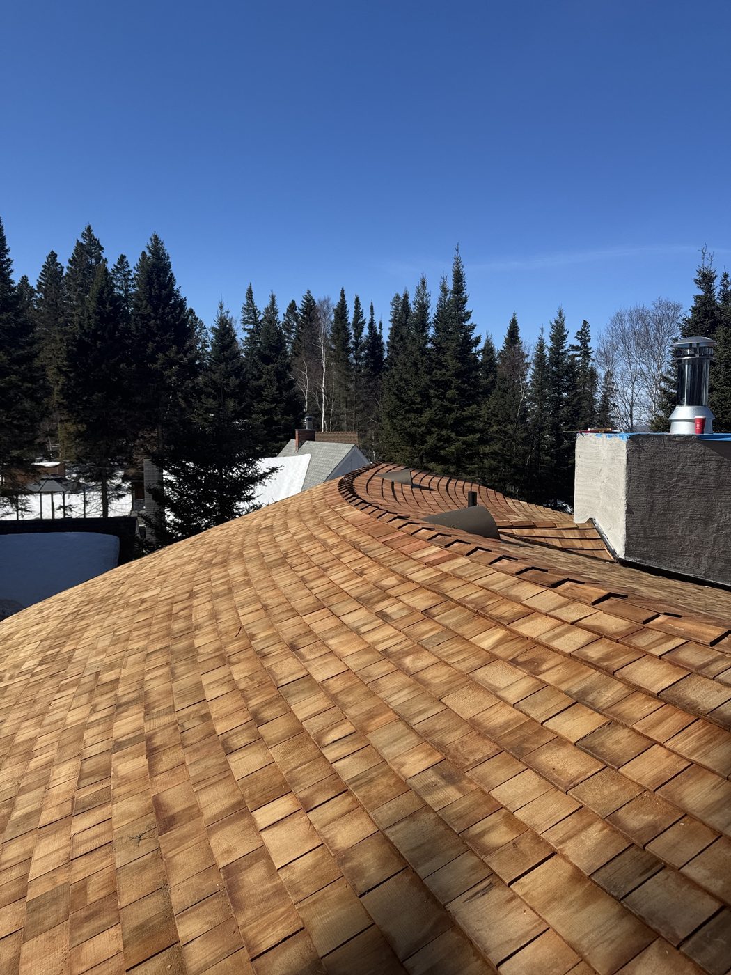 Sweeping curved cedar shake roof against blue sky